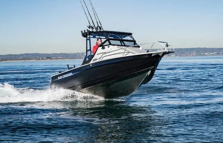 Man in a red top driving a C-Series boat across water