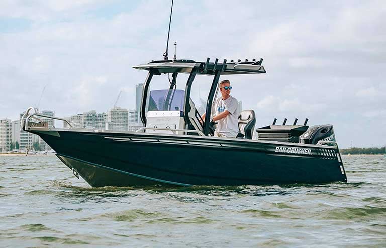 Man in a white shirt and sunglasses driving XT series boat